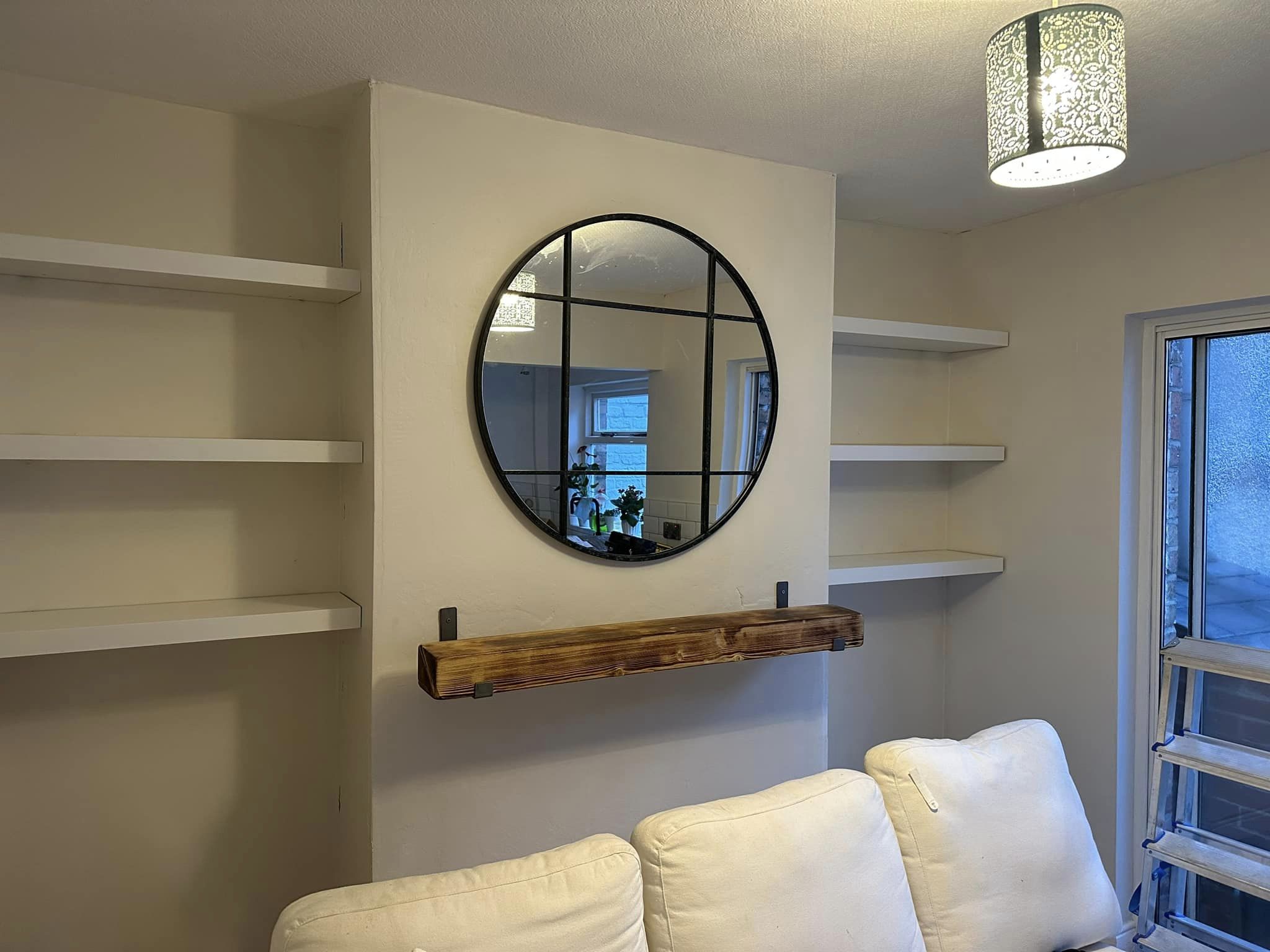 Circle mirror in living room with fitted shelving